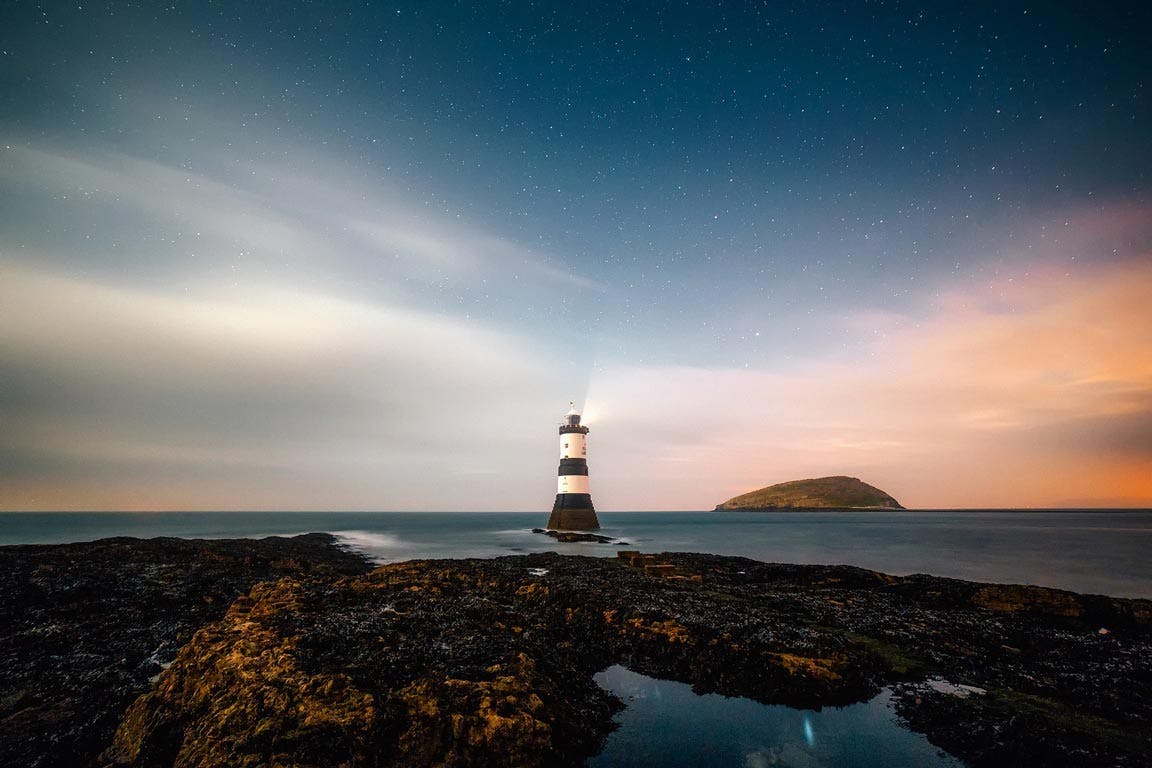 Leuchtturm an der Küste in der Nacht mit Sternenhimmel