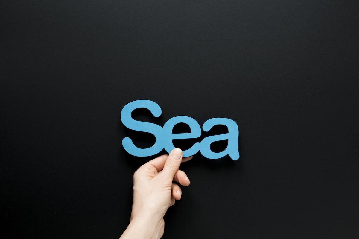 Hand hält SEA-Schriftzug in die Höhe